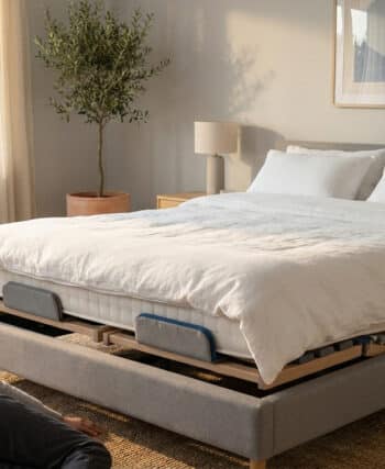 Une personne allongée près d'un sommier ergonomique dans une chambre lumineuse et moderne.