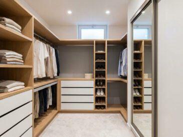 Petit dressing en U avec étagères en bois clair, tiroirs blancs, penderies et miroir, parfaitement agencé.