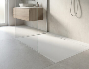 Receveur de douche blanc extra plat dans une salle de bain moderne avec paroi en verre et meuble vasque en bois.
