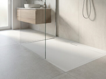 Receveur de douche blanc extra plat dans une salle de bain moderne avec paroi en verre et meuble vasque en bois.